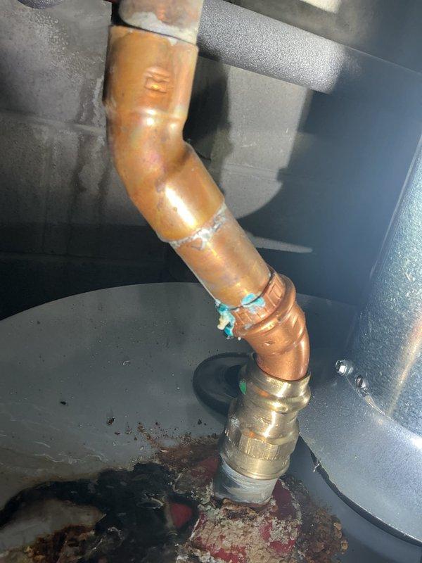 Conducted inspection of water heater exhibiting significant leakage from top surface. Observed extensive corrosion damage on upper portion of tank with visible moisture accumulation, compromised copper pipe connections showing greenish corrosion at joints, and mineral buildup around brass fittings. Documented evidence of advanced deterioration requiring replacement recommendation.