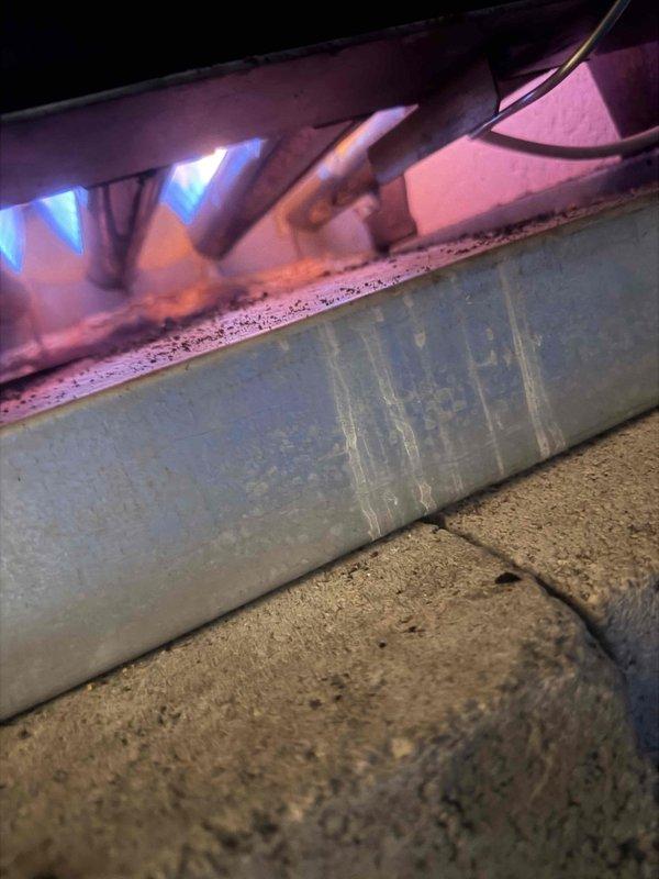 Responded to no-heat call for a relatively new boiler system. Diagnosed communication failure between thermostat and boiler control unit. Observed normal blue flame operation at burners but detected significant corrosion along the heat exchanger, indicating possible condensate drainage issues affecting electrical components. Restored communication functionality and verified proper system operation.