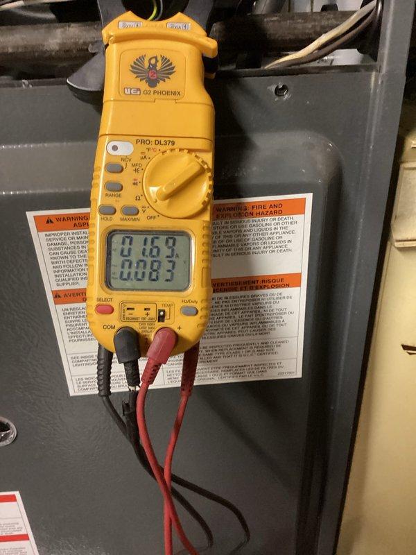 Performed routine heating system maintenance service on furnace. Inspected blower wheel assembly for proper operation and cleaned visible corrosion from central mounting hardware. Conducted electrical diagnostics with digital multimeter, verifying current readings of 0.163 and 0.003 amps on system components to ensure proper electrical function.