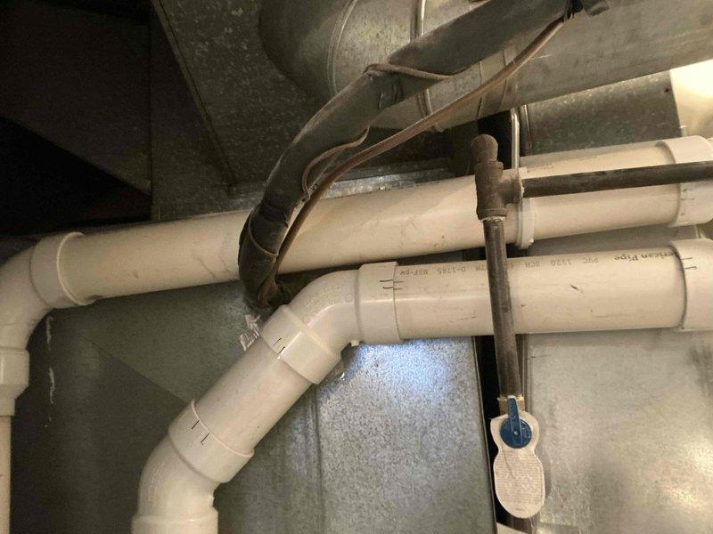 Conducted full system inspection of existing forced air HVAC equipment including outdoor AC condenser unit showing signs of weathering and environmental exposure. Evaluated current ductwork configuration and drainage system consisting of PVC piping and metal hanging hardware in utility area. Presented replacement options for complete HVAC system and hot water tank to improve efficiency and reliability.