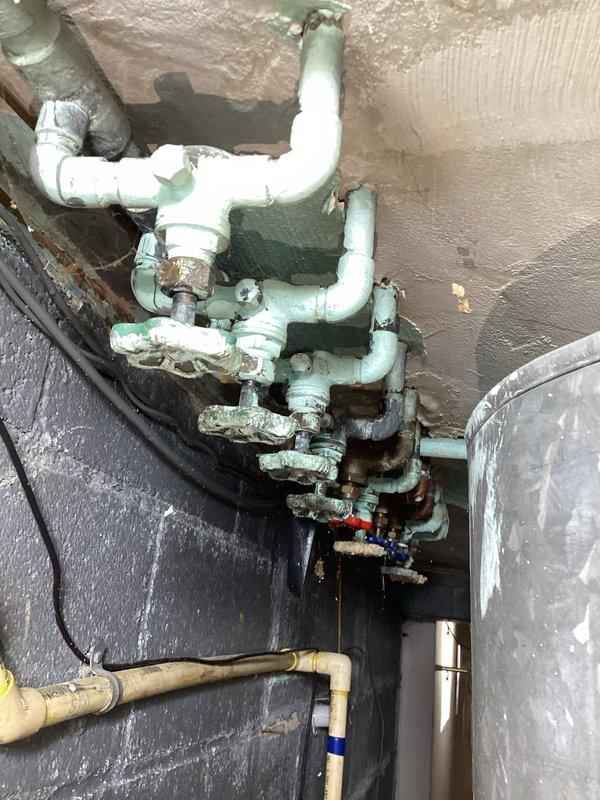 Conducted comprehensive inspection of aging plumbing system with significant corrosion observed on multiple valves and pipe connections. Documented extensive deterioration including peeling paint, exposed materials, and possible moisture damage to surrounding walls and ceiling. Photos taken of all affected areas to support quotation for recommended repairs and potential system replacement.