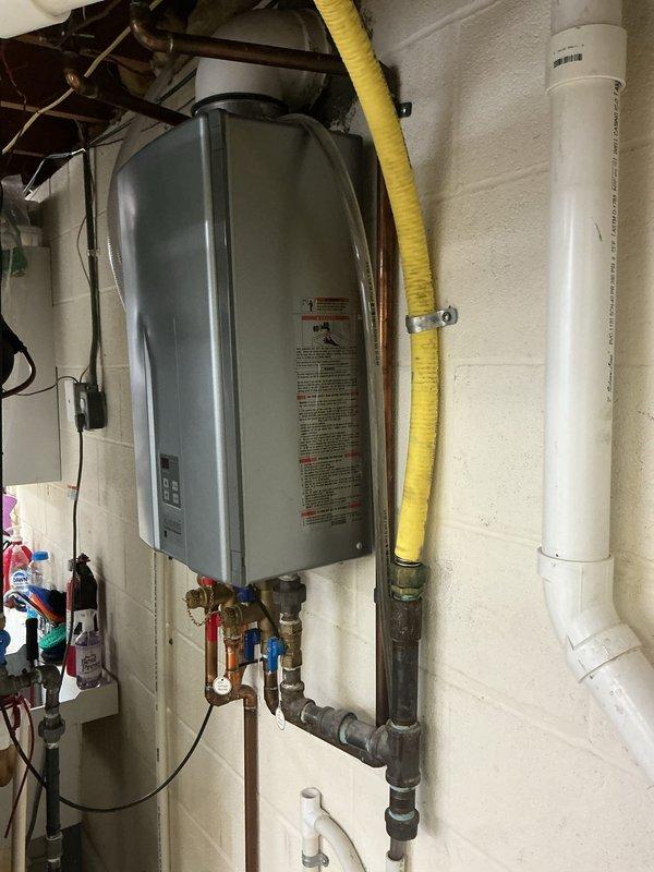 Performed scheduled maintenance service on a tankless water heater system. Inspected internal components after removing front panel, examining control board, wiring connections, and heat exchanger. Verified proper venting through PVC exhaust system and confirmed all plumbing connections were secure with no signs of leakage at copper supply lines.