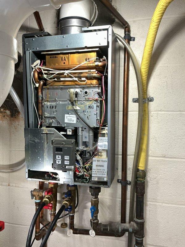 Performed scheduled maintenance service on a tankless water heater system. Inspected internal components after removing front panel, examining control board, wiring connections, and heat exchanger. Verified proper venting through PVC exhaust system and confirmed all plumbing connections were secure with no signs of leakage at copper supply lines.