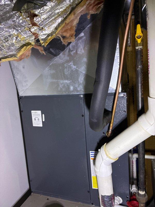 Conducted furnace replacement consultation and documented existing installation setup in utility area. Photographed current furnace/air handler unit with connected ductwork, refrigerant lines, and PVC condensate system. Additional documentation included inspection of PEX piping installation between floor joists and electrical wiring configuration to ensure proper integration with potential replacement options.