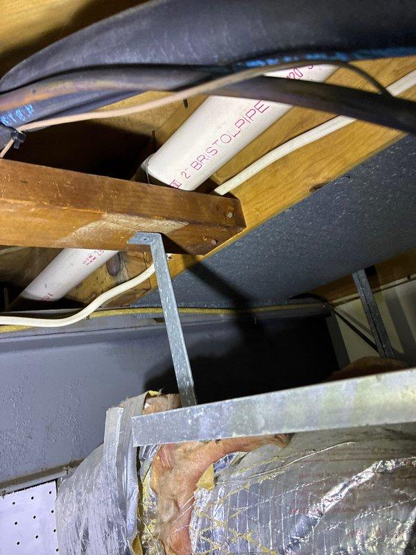 Conducted furnace replacement consultation and documented existing installation setup in utility area. Photographed current furnace/air handler unit with connected ductwork, refrigerant lines, and PVC condensate system. Additional documentation included inspection of PEX piping installation between floor joists and electrical wiring configuration to ensure proper integration with potential replacement options.