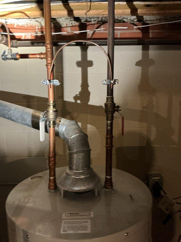 Conducted comprehensive assessment of aging water heater system including tank condition, connection points, and ventilation ductwork. Identified deterioration at duct-wall junction with visible cracking and potential leakage concerns. Documented existing copper supply lines, pressure relief valve, and galvanized elbow configuration for replacement specifications.