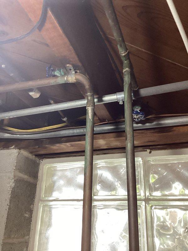 Conducted comprehensive plumbing inspection of copper supply lines and associated fittings in utility area. Documented existing installation showing signs of oxidation at connection points and examined insulated mechanical components along concrete block wall. Photographed all components for documentation purposes with special attention to pipe junctions and previous repair work.