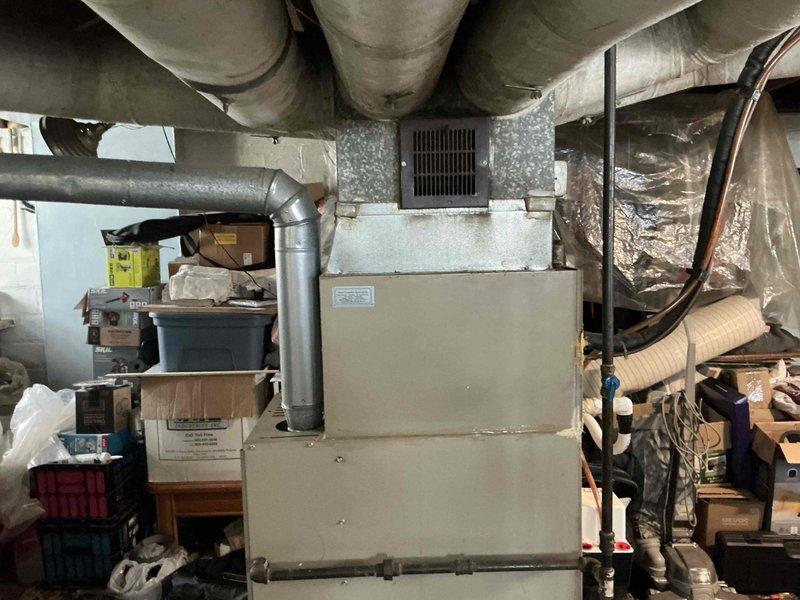 Conducted assessment of 17-year-old R22 HVAC system located in basement utility area. System shows significant age-related wear requiring replacement. Provided customer with two quotes: AC options and a full system replacement quote as requested. Equipment inspection revealed outdated furnace with connected ductwork and exhaust components still functional but approaching end of serviceable life.