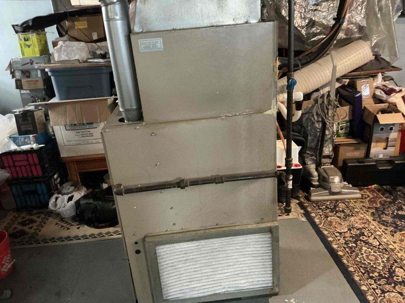 Conducted assessment of 17-year-old R22 HVAC system located in basement utility area. System shows significant age-related wear requiring replacement. Provided customer with two quotes: AC options and a full system replacement quote as requested. Equipment inspection revealed outdated furnace with connected ductwork and exhaust components still functional but approaching end of serviceable life.