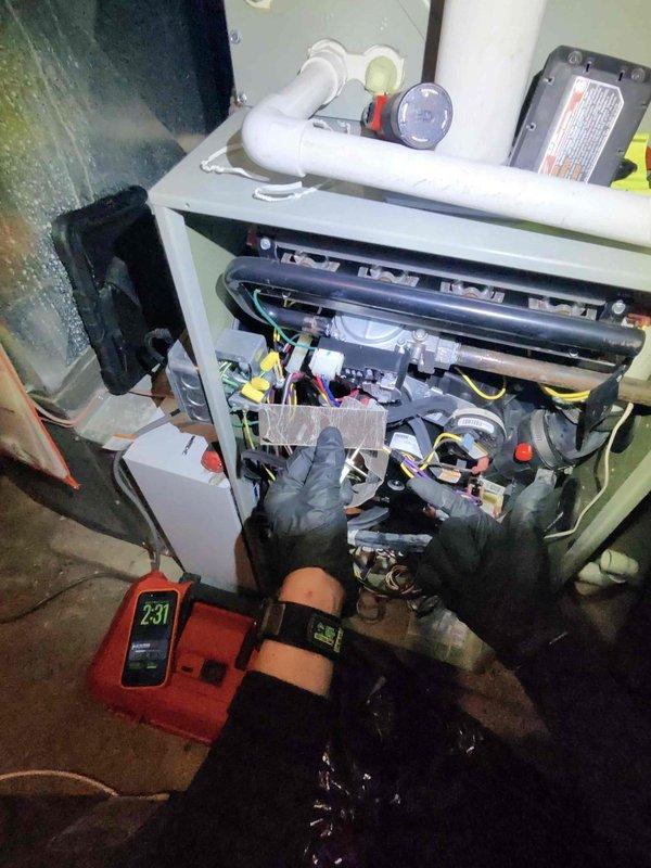 Performed comprehensive maintenance on residential heating system. Conducted electrical testing with multimeter showing 231V reading at unit terminals. Accessed ceiling-mounted air handler using extension ladder and inspected internal components including wiring connections and PVC condensate lines.