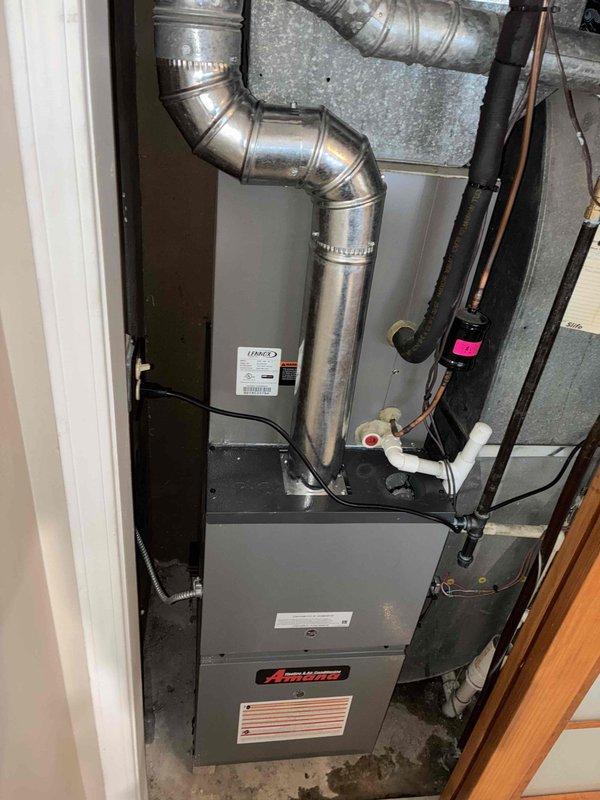 Successfully installed an Amana furnace unit with complete ductwork integration, including proper connection of galvanized sheet metal ducts secured with metal clamps. System installation included connection of copper lines and PVC drainage components, with all plumbing infrastructure properly integrated to ensure optimal functionality of the new heating system.