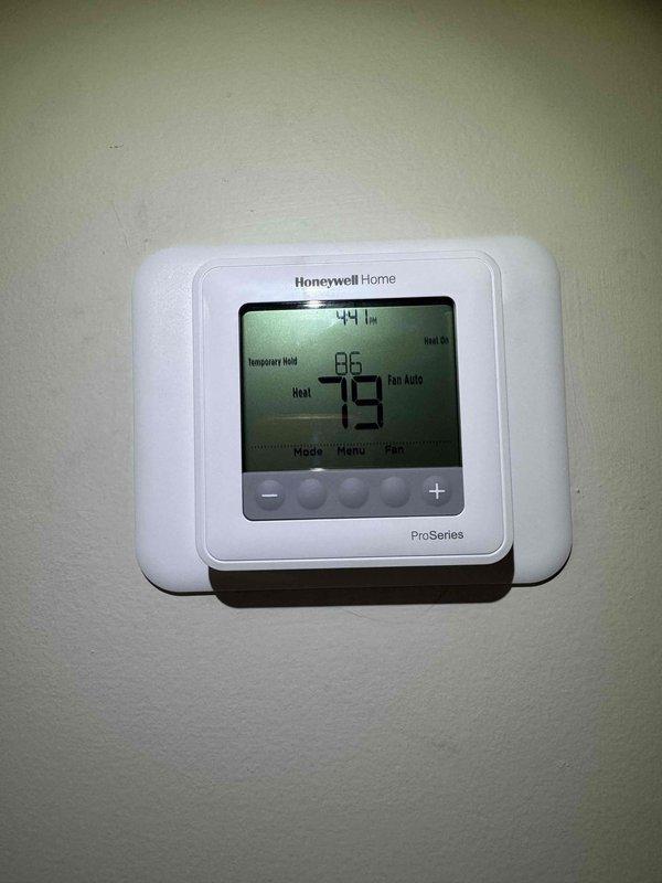 Responded to service call regarding thermostat error message. Removed thermostat wall plate to inspect wiring connections, then reinstalled and tested Honeywell Home ProSeries digital thermostat. Confirmed proper operation with heat set to 79°F and humidity reading at 44%.