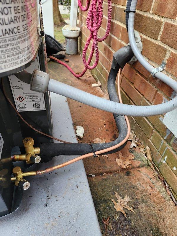 Completed installation of new outdoor A/C unit on concrete pad adjacent to brick exterior wall. System installation included proper mounting of disconnect box, running of copper refrigerant lines with insulation, and connection of all necessary electrical components. All service valves were properly installed and system was verified operational with appropriate line set routing and electrical connections completed according to manufacturer specifications.