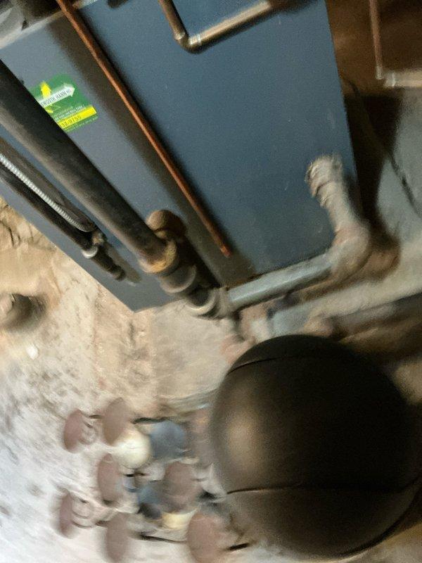 Performed assessment of leaking boiler system in utility area. Unit shows signs of water leakage requiring repair. Documented existing installation including blue heating unit with copper supply lines, electrical connections, and associated plumbing to provide client with repair options.