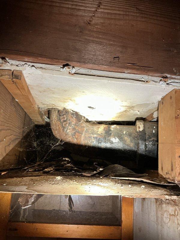 # Plumbing Site Visit Summary

Conducted comprehensive plumbing inspection of residential property focusing on crawl space and utility areas. Documented extensive deterioration of cast iron drainage piping showing advanced corrosion, surface scaling, and rust staining throughout accessible sections. Identified compromised ceiling materials in utility space with water damage patterns and structural separation from framing members. Observed exposed plumbing infrastructure including vertical supply and waste lines requiring further assessment. Photographed conditions of insulation displacement, organic debris accumulation in crawl space, and overall system age-related degradation for client review and repair planning recommendations.