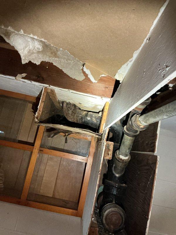 # Plumbing Site Visit Summary

Conducted comprehensive plumbing inspection of residential property focusing on crawl space and utility areas. Documented extensive deterioration of cast iron drainage piping showing advanced corrosion, surface scaling, and rust staining throughout accessible sections. Identified compromised ceiling materials in utility space with water damage patterns and structural separation from framing members. Observed exposed plumbing infrastructure including vertical supply and waste lines requiring further assessment. Photographed conditions of insulation displacement, organic debris accumulation in crawl space, and overall system age-related degradation for client review and repair planning recommendations.