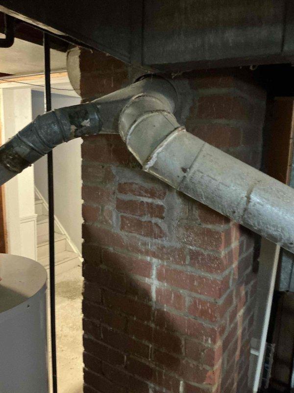 Responded to no heat call on forced air system. Evaluated existing furnace and determined unit required replacement. Provided customer with three gas furnace replacement options ranging from 80% to 96% nominal AFUE efficiency ratings. Documented existing ductwork configuration in basement utility area, including metal supply ductwork with white painted lower enclosure and flexible connector components. Photographed installation area showing exposed brick walls, concrete flooring, and current HVAC infrastructure to support replacement estimate and planning.