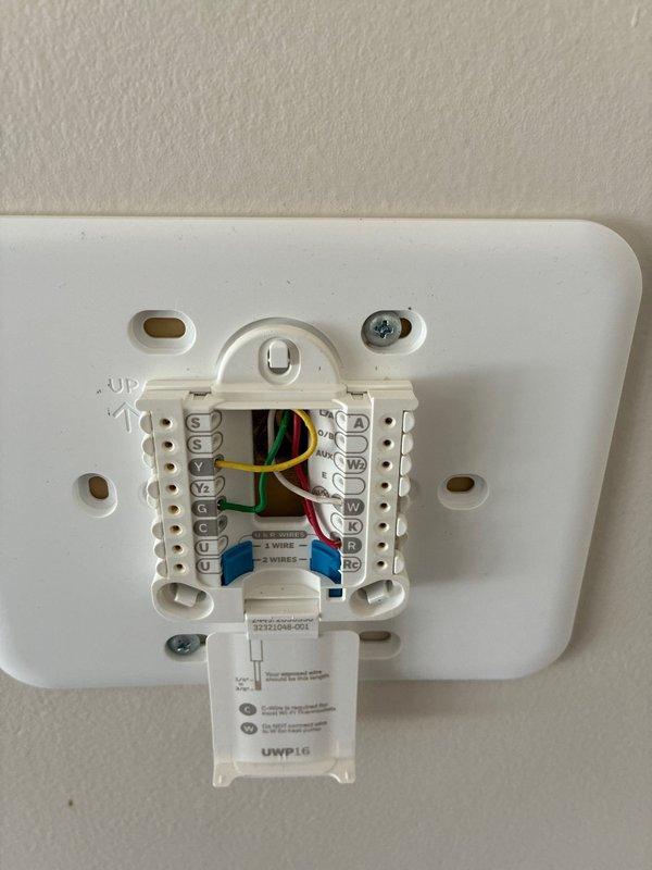 Performed comprehensive assessment of 22-year-old residential furnace system requiring replacement evaluation. Documented existing HVAC infrastructure including exterior condensate drainage configuration and interior thermostat wiring connections with multiple wire terminals (Y, G, R, W, C) to facilitate equipment replacement planning and ensure proper system integration.