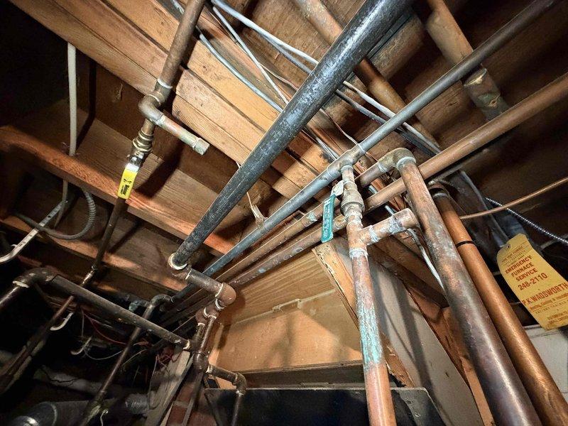Responded to service call for boiler leaking onto floor. Upon inspection, identified active water leak in boiler piping system located in basement utility area. Documented existing plumbing configuration including copper supply lines, galvanized piping, and associated valve assemblies showing signs of age and oxidation. Photographed leak source and surrounding infrastructure for service records and recommended appropriate repairs to resolve water discharge issue.