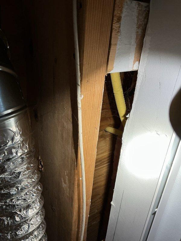 Responded to report of gas leak originating from beneath kitchen area in basement. Upon inspection, accessed crawl space and examined exposed gas piping system running through ceiling joists. Located copper gas line with brass fittings and connections running horizontally through the space. Conducted visual inspection of all accessible gas line sections, joints, and fittings for signs of leakage or damage. Documented existing piping configuration including routing near PVC plumbing lines and HVAC ductwork. Further pressure testing recommended to confirm leak location and ensure system integrity before proceeding with repairs.