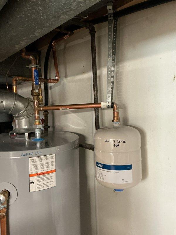 Returned to property to complete previously initiated repairs on the water heating system. Removed and replaced the failed expansion tank with a new unit, properly mounting it to the wall with secure strapping and marking it with installation date and pressure specifications. Completed copper pipe repairs on the water supply lines, installing new fittings and joints to address leaking connections. Installed a new valve in the system as indicated by labeling. All copper connections were properly soldered and tested for leaks. The expansion tank was pressurized to 60 PSI and integrated into the piping network. Verified proper operation of all components, including the water heater connections, shut-off valves, and the newly installed expansion tank. System was tested and confirmed to be functioning correctly with no active leaks upon completion.