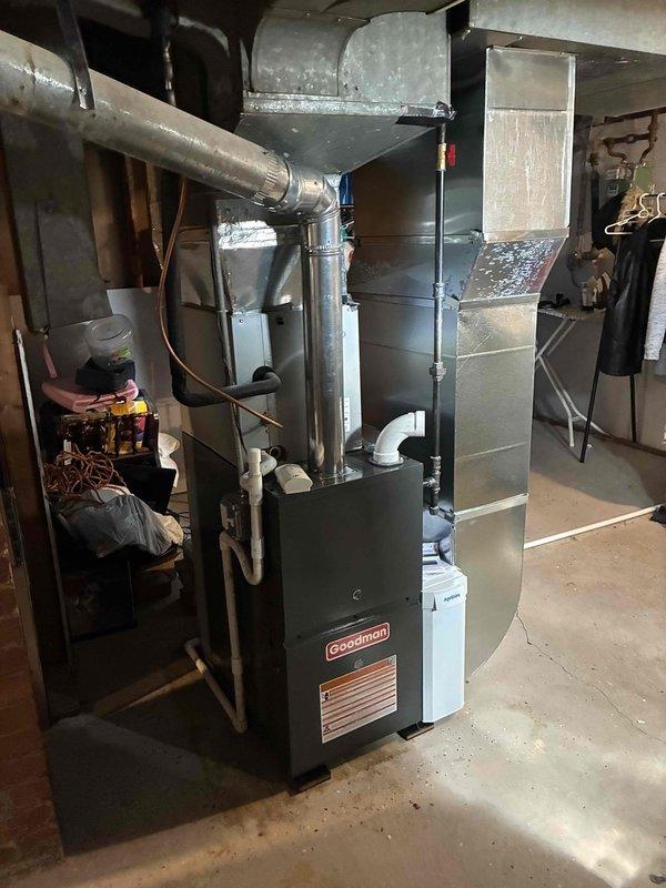 Completed installation of new Goodman 80% efficiency furnace in residential basement mechanical room. Unit installed on concrete pad with proper clearances, connected to existing ductwork system via galvanized metal plenum and distribution network, and tested for proper operation and airflow.