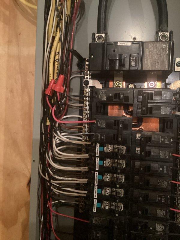 Installed whole home surge protection device at main electrical panel. Device mounted on plywood wall adjacent to 200-amp main breaker panel, with proper wiring connections made to protect entire electrical system from voltage spikes and power surges. Unit operational with green indicator light confirming active protection status.