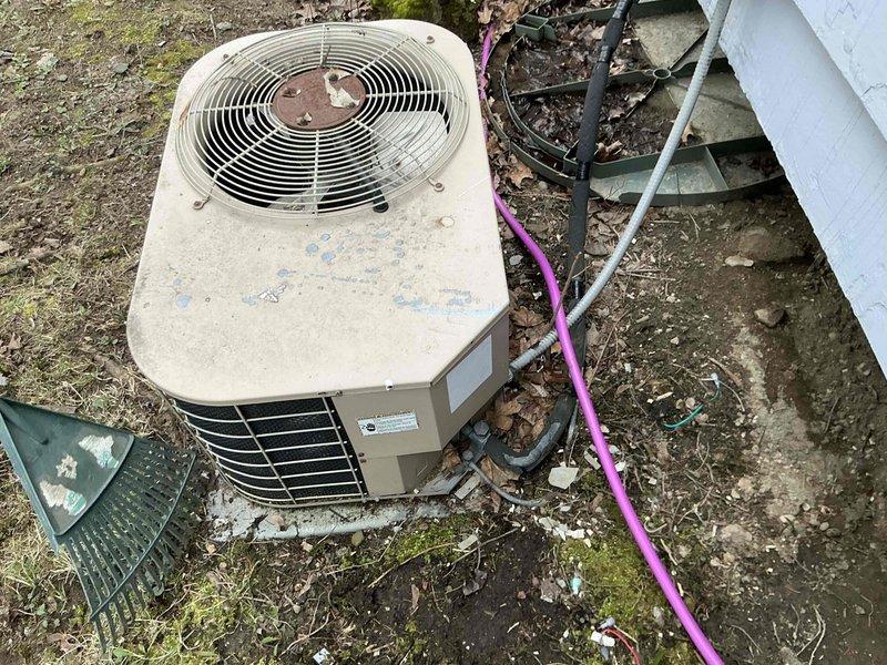 Conducted comprehensive evaluation of existing HVAC system for replacement estimate. Assessed outdoor condensing unit showing significant weathering, surface deterioration, and debris accumulation on exterior pad. Documented indoor furnace assembly with integrated humidifier system and associated ductwork configuration in basement mechanical room. Photographed current equipment conditions, refrigerant line routing, electrical connections, and ductwork layout to provide replacement options and system specifications.