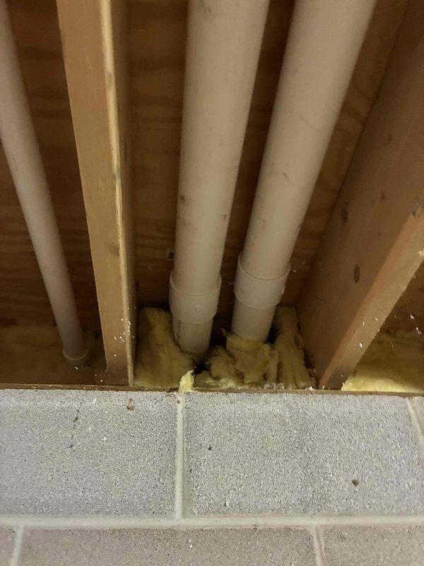 Completed installation of 96% efficiency furnace with scrubber system, including proper venting with white PVC piping routed through existing wall cavity with fiberglass insulation for weatherization. Electrical outlet box with GFCI protection mounted to unit panel, with coordination noted for licensed electrician to complete surge protector installation at later time.