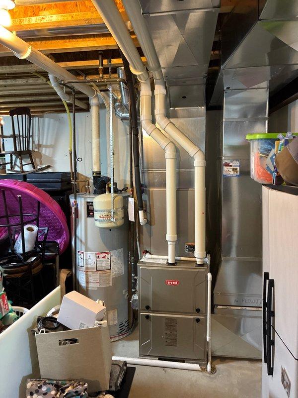 Conducted on-site evaluation for complete HVAC system replacement in residential basement utility area. Assessed existing Bryant furnace unit and adjacent water heater for replacement options, documented current ductwork configuration including main trunk lines and PVC venting system, and provided comprehensive quote for full system replacement with water heater upgrade.
