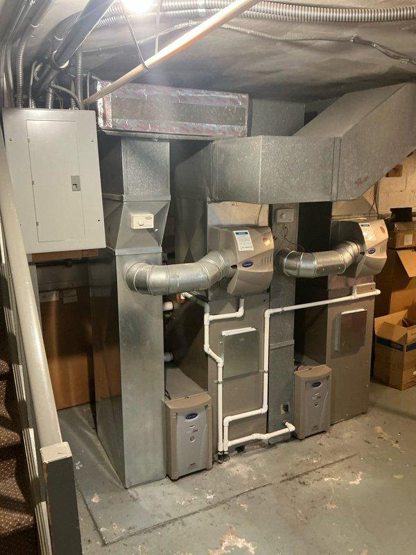 Conducted comprehensive assessment of existing HVAC infrastructure consisting of multiple Carrier heating and cooling systems located in basement mechanical room. Evaluated current multi-zone configuration with two furnace units and associated air handling equipment for potential replacement options. Customer requested comparative estimates for three replacement scenarios: two complete system replacements, two furnace replacements, and one furnace replacement as alternatives to previously quoted repair work. Documented existing equipment layout including centralized ductwork distribution, flexible and rigid duct runs, PVC condensate drainage lines, and electrical service panel configuration to support accurate replacement system specifications and installation planning.