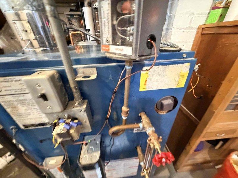 Responded to no heat call where homeowner reported boiler failure potentially caused by another contractor's underground plumbing work in basement. Upon arrival, inspected blue residential boiler unit and associated electrical wiring for damage or disconnections. Verified power supply to unit, checked control wiring connections, and examined thermostat circuit for breaks or loose connections that may have occurred during excavation work. Traced electrical runs and confirmed all safety controls, limit switches, and transformer connections were intact. Restored power to boiler, verified proper ignition sequence, and confirmed unit returned to normal heating operation. Documented existing mechanical room conditions with photographs showing copper piping, gas connections, and electrical infrastructure. Unit tested successfully with no further issues noted at time of service.