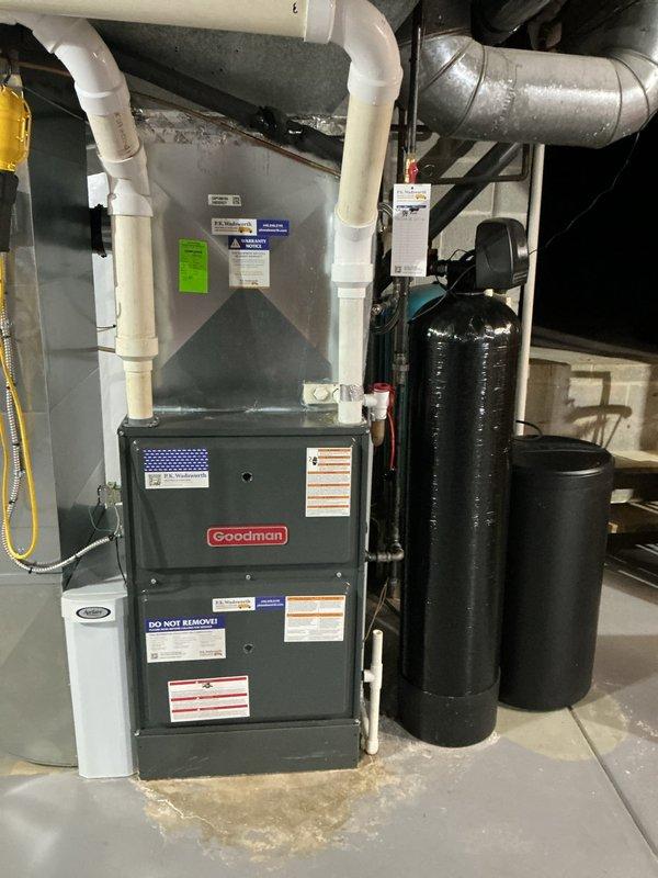 Responded to callback for humidifier leaking issue that was previously serviced. Upon arrival, inspected Clean Comfort humidifier system integrated with Goodman furnace and found persistent water leakage at base of unit. Diagnosed failed solenoid valve and improper water feed line connection causing overflow condition. Replaced defective solenoid valve, adjusted water supply pressure, and secured all plumbing connections to manufacturer specifications. Tested humidifier through multiple cycles to verify proper operation and confirmed no additional leakage present. System operating correctly at time of departure.