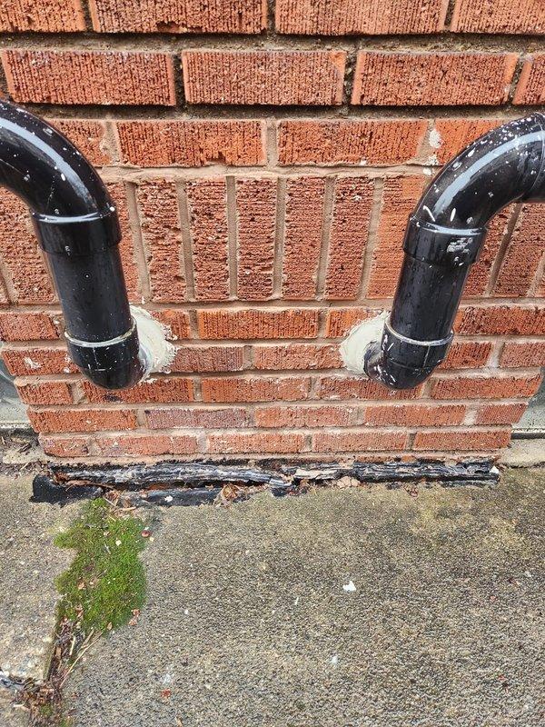 Eliminated prohibited saddle valve connection on humidifier water supply line and replaced with code-compliant plumbing installation. Removed non-approved joints and fittings, ensuring all connections meet current mechanical code requirements. Documented all modifications with photographs showing exterior drainage components and foundation area where work was performed.