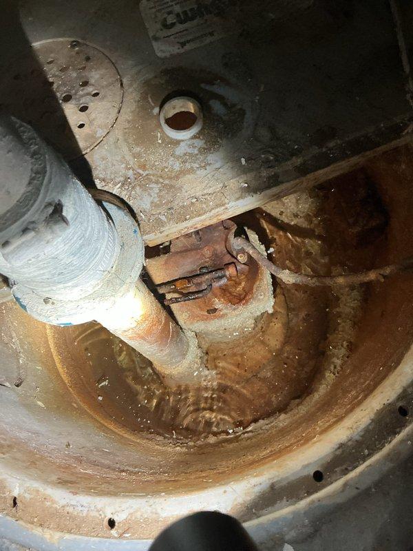 Responded to service call for non-operational sump pump system requiring replacement. Upon inspection, found existing sump pump basin and components exhibiting severe corrosion, rust accumulation, and standing water with rust-colored sediment. The interior of the sump pit displayed extensive deterioration with compromised metal surfaces, corroded piping connections, and degraded mechanical components. Documented existing conditions showing failed pump assembly with heavily oxidized basin, deteriorated discharge piping with white PVC connections, and significant rust buildup throughout the system indicating prolonged exposure to moisture and lack of functionality.
