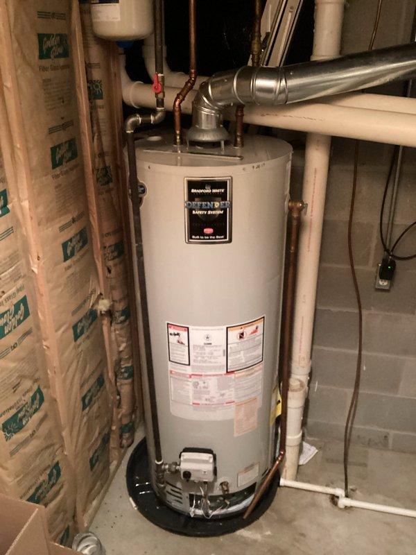Responded to no hot water complaint at residential property. Upon arrival, inspected tanked water heater installation in basement utility area. Evaluated gas control valve assembly, thermocouple connections, and pilot light operation. Checked electrical connections to control box and verified proper wiring to white and red leads. Inspected copper supply lines, brass fittings, and shut-off valves for proper operation. Assessed venting system including metallic ductwork connections at top of unit. Verified all safety labels and warning stickers were intact and legible. Diagnosed issue and restored hot water service to residence.