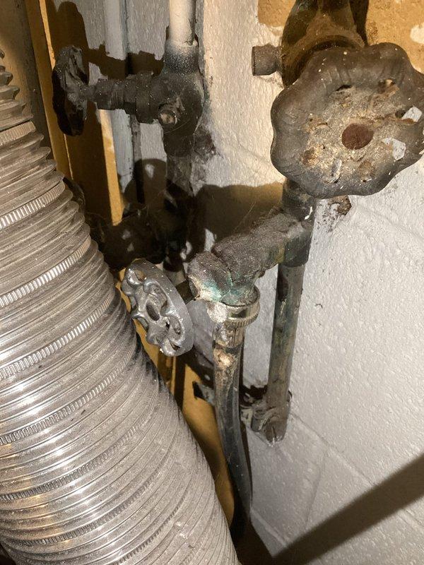 Completed comprehensive plumbing inspection of water heater installation and associated fixtures. Documented existing conditions including corroded shutoff valves, aged metal components with significant oxidation, P-trap configuration beneath water heater with staining at PVC joints, and deteriorated valve assemblies requiring future attention for proper system maintenance.