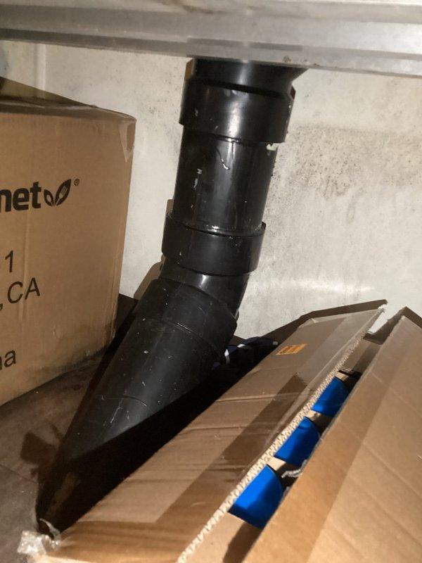 Conducted plumbing estimate for basement piping replacement. Assessed existing black PVC drainage system with 90-degree elbow configuration mounted against concrete block wall. Documented current pipe condition, including visible sealant application at connection points and overall system layout. Photographed installation to provide comprehensive evaluation for required piping replacement work in utility area.