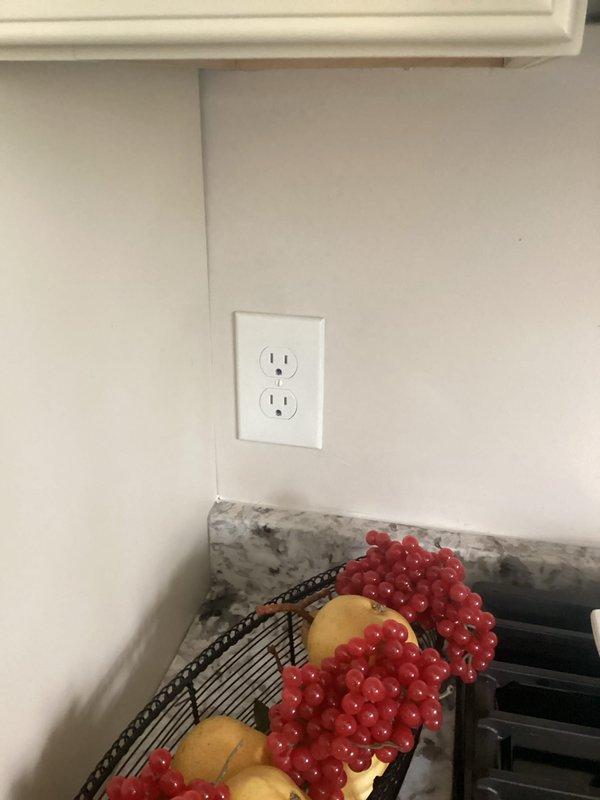 Completed comprehensive electrical inspection of residential property. Documented existing electrical panel configuration showing properly organized circuit breakers and wiring, verified kitchen GFCI outlet installation and functionality, and photographed panel-mounted environmental controls for client records.