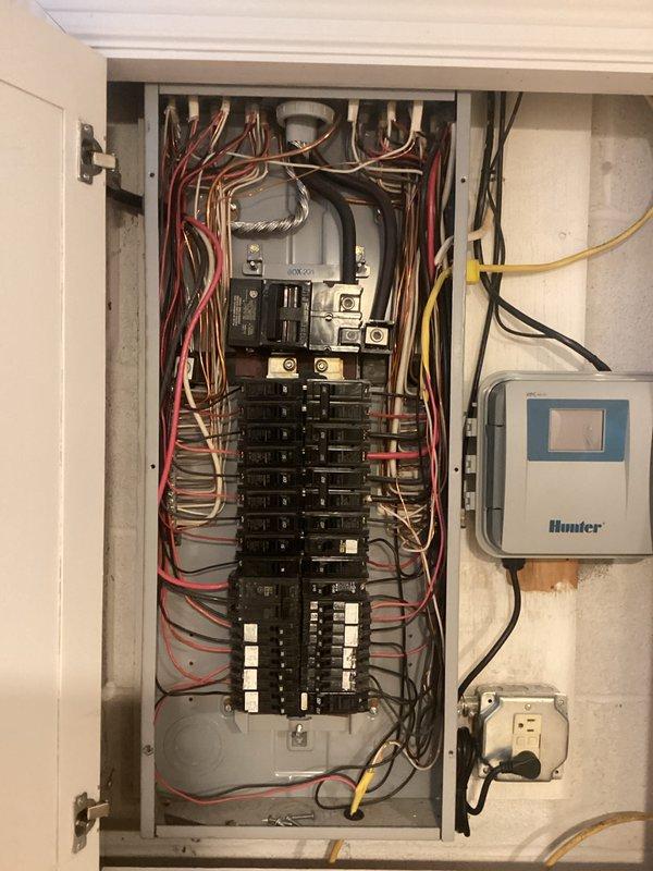 Completed comprehensive electrical inspection of residential property. Documented existing electrical panel configuration showing properly organized circuit breakers and wiring, verified kitchen GFCI outlet installation and functionality, and photographed panel-mounted environmental controls for client records.