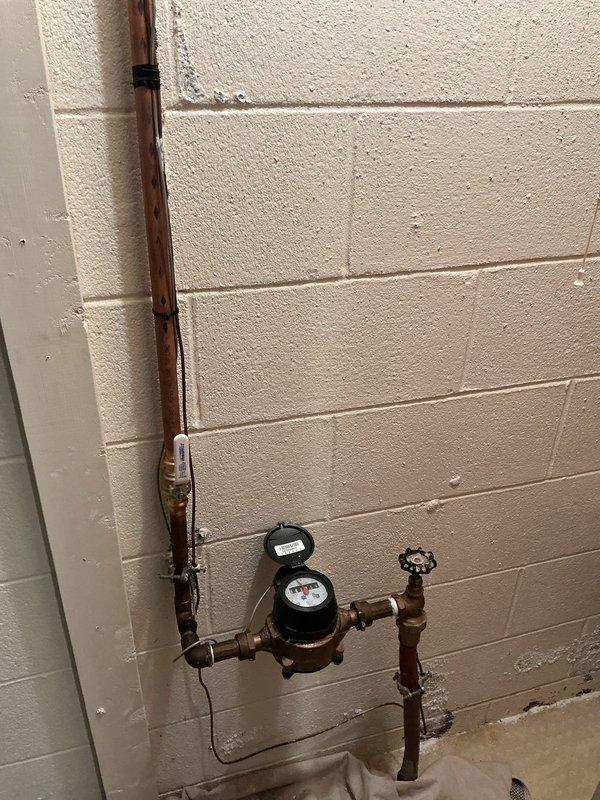 Installed two 1/2-inch ball valves in the access panel to provide individual shut-off capability for the second-floor shower fixture. Accessed the plumbing lines through the existing utility room access point where the water supply lines were located behind the painted concrete block wall. The new ball valves were installed on the hot and cold water supply lines serving the chrome shower valve assembly, allowing for future maintenance and repairs to be completed without shutting off water to the entire home.