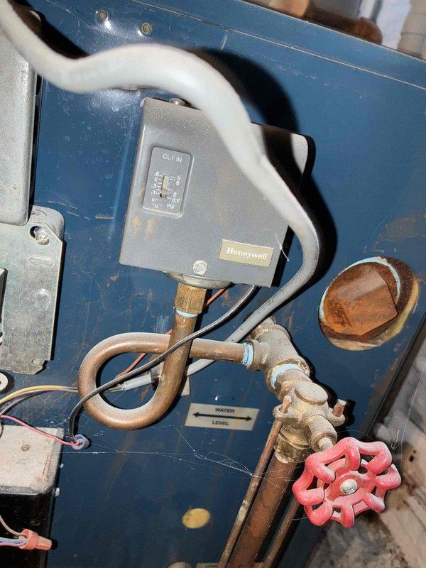 Completed comprehensive boiler maintenance inspection and documentation. Examined and photographed key system components including Honeywell control unit, water level indicators, supply and return piping, isolation valves, and associated mechanical connections. Documented significant corrosion present on vertical drainage piping and coupling joints, noting heavy rust accumulation and mineral deposits that may require future attention to prevent system integrity issues.