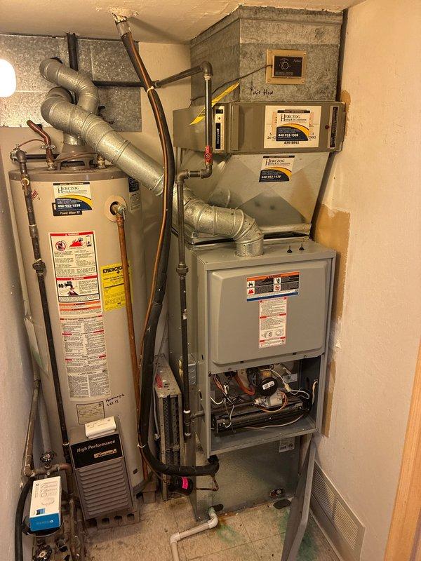Performed comprehensive assessment of existing HVAC system for full replacement estimate. Documented current equipment configuration including 3-ton Goodman condensing unit (Model 4AC13L30P-7A) charged with R-410A refrigerant, gas furnace with air handler, and integrated water heater installation in utility closet. Photographed manufacturer data plates showing electrical specifications of 208/230V single-phase operation and equipment serial numbers for replacement planning. Evaluated cramped mechanical room layout with vertically stacked components to determine optimal replacement equipment sizing and installation approach for complete system upgrade.