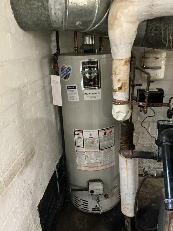 Responded to service call for non-functioning water heater with no hot water production and suspected water leak. Upon inspection, examined internal components including sight glass and electrical connections, and assessed overall condition of tanked water heater unit showing age-related wear with rust staining on piping and connections. Documented equipment condition and identified issues affecting hot water system performance.