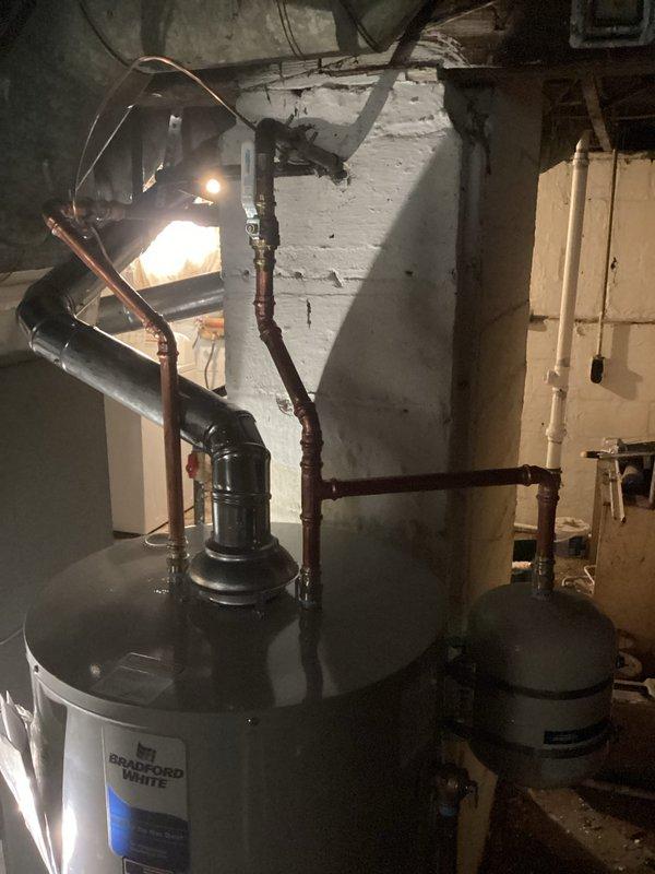 Responded to emergency call for burst water heater in basement. Removed and disposed of failed Bradford White tank-style water heater showing significant age-related deterioration including surface wear, paint cracking, and general weathering. Installed new residential tank water heater with proper copper piping connections, ensuring all plumbing connections were secure and code-compliant. Tested new unit for proper operation and verified no leaks in system.
