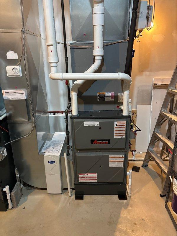 Completed installation of new 96% AFUE high-efficiency Amana furnace system in residential basement utility area. Installed furnace unit with proper venting configuration using white PVC piping for intake and exhaust, routed vertically and horizontally with appropriate elbows and connections to exterior. Connected furnace to existing ductwork system and verified all sheet metal connections were secure. Installed electrical connections via proper conduit, ensured all safety labels and manufacturer specifications were visible and intact. Tested system operation and confirmed proper combustion efficiency and airflow throughout distribution system.