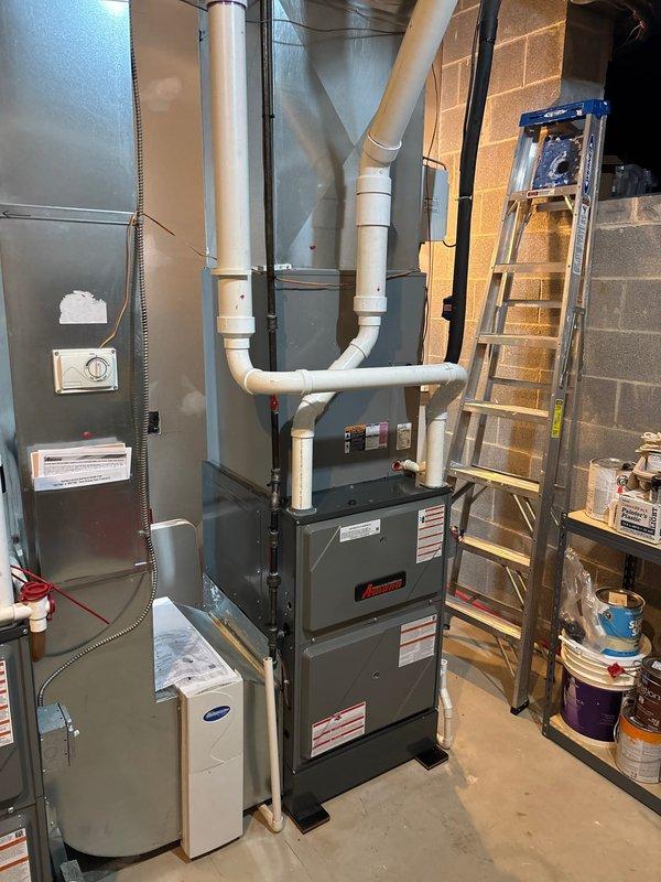 Completed installation of new 96% AFUE high-efficiency Amana furnace system in residential basement utility area. Installed furnace unit with proper venting configuration using white PVC piping for intake and exhaust, routed vertically and horizontally with appropriate elbows and connections to exterior. Connected furnace to existing ductwork system and verified all sheet metal connections were secure. Installed electrical connections via proper conduit, ensured all safety labels and manufacturer specifications were visible and intact. Tested system operation and confirmed proper combustion efficiency and airflow throughout distribution system.