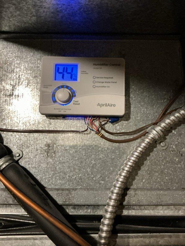 Completed comprehensive heating system maintenance on Carrier air handler unit. Inspected and verified proper operation of AprilAire whole-home humidifier system, confirming digital control display reading 44% relative humidity with all indicator lights functioning correctly. Checked humidifier water panel condition, electrical connections, and control settings. Examined air handler cabinet, verified manufacturer specifications, and inspected all associated ductwork connections. Assessed condensate drainage system and PVC piping for proper operation and secure connections. All components found operating within normal parameters with no service requirements indicated at time of inspection.