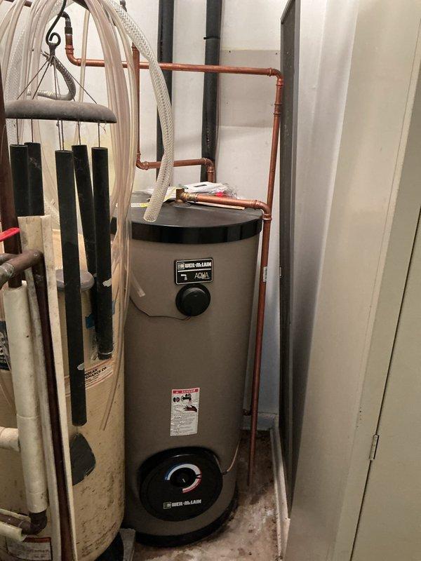Responded to service call for reported boiler leak at residential property. Upon inspection, identified Weil-McLain Aqua Plus water heater unit with visible moisture concerns. Evaluated copper piping connections at top of unit and assessed all plumbing joints for potential leak sources. Documented equipment condition and piping configuration for service records.