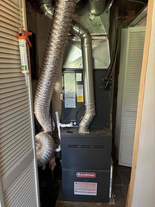 Completed installation of new Goodman air conditioning system in residential utility closet. Installed AC condenser unit utilizing R32 refrigerant, connected all ductwork including metallic supply plenum and insulated flex duct distribution, and verified proper electrical connections to existing furnace for integrated system operation.